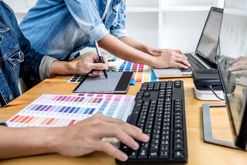 Obraz na płótnie Canvas Two colleagues creative graphic designer working on color selection and drawing on graphics tablet at workplace, Color swatch samples chart for selection coloring