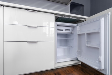 Fototapeta premium A small refrigerator built into the cabinet with drawers in the kitchen.