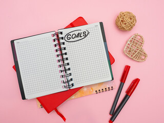 top view of an open notebook with blank pages and goal inscription on pink table