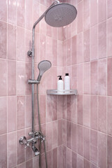 Bottles for shampoo and gel in the bathroom against the backdrop of pink tiles and shower.
