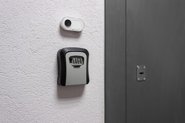 Key box with a combination lock next to the door and a bell button on the wall