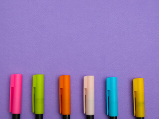 top view of different colorfull pens or markers isolated on purple paper background