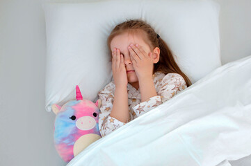 Frightened girl who sleeps in her bed with her eyes open. The child is afraid of the dark....