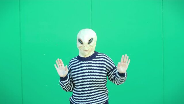 People wearing alien mask dancing against a green chroma key background. Concept of happiness and excited emotions. Joyful extraterrestrial ufo concept dance