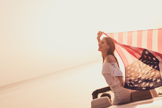 Photo of sweet attractive husband wife wear white outfits smiling riding automobile rising stars stripes flag outside country side route - Powered by Adobe