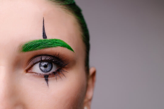 Woman with creative joker  clown makeup. Trendy halloween green carnival costume. Eye close-up macro. Stylish fantasy glamorous make-up. Madness. crazy anxiety image mood. Copy space banner