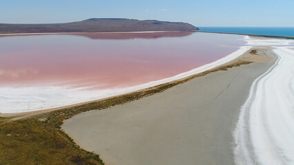 Top view of beautiful landscape with pink lake. Shot. Extraterrestrial miracle of nature-lake with pink water. Beautiful landscape with pink lake, white sand and mountains on horizon