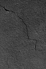 Gray wall with a crack. Texture of rough plaster with uneven granular coating