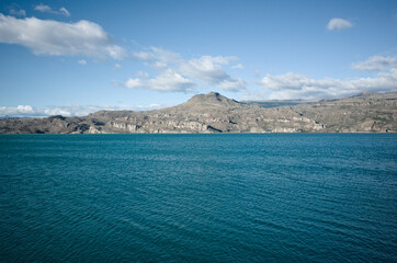 Obraz premium View of mountains from shore of Lago General Carrera Lake, Puerto Ibanez, Aysen Province, Chile. Summer day at glacial lake with clear bright blue water and light ripples on water in Chilean Patagonia