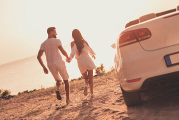Rear back behind view portrait of handsome beautiful cheerful dreamy couple running to water having...