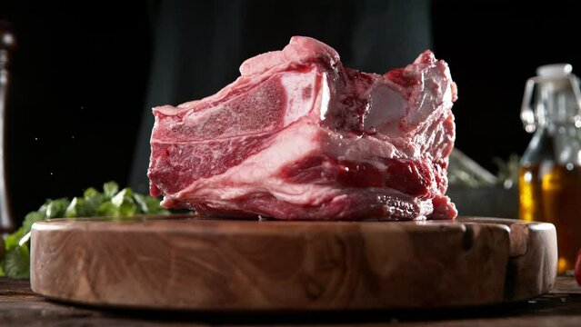 Flying piece of raw beef steak falling on cutting board. Meat preparation in kitchen. Filmed on high speed cinema camera, 1000 fps.