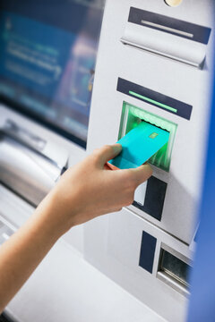 Close-up Of A Young Woman's Hand Inserting A Credit Card Into An ATM Bank Machine To Transfer Money Or Withdraw. Finance Customer And Banking Service Concept. Vertical Shot