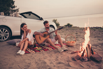Full length body size photo young couple enjoying music near fire on beach near cabriolet car