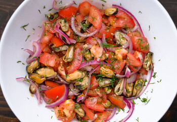 Salad with mussels and tomatoes and red onion in white plate. Concept of healthy diet food. Flat lay.