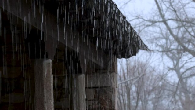 Rain water falling from roof. Severe storm over the wooden roof.