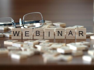 webinar word or concept represented by wooden letter tiles on a wooden table with glasses and a book