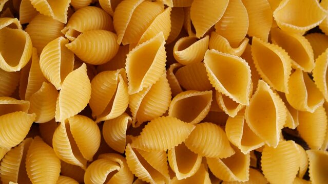 Close up of raw italian shell shaped pasta on rotating table. 4k footage