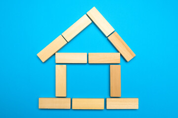 House of wooden blocks on a blue background. Layout of the house out of wooden sticks. Real estate concept. Free copy space.