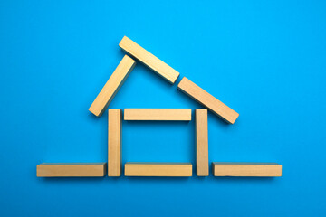 House made of wooden blocks on a blue background. Layout of the house out of wooden sticks. Real estate concept. Free copy space.