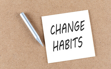 CHANGE HABITS text on sticky note on a cork board with pencil ,