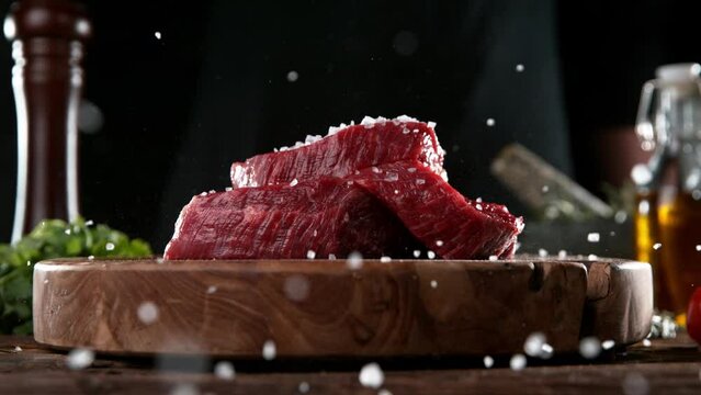 Super slow motion of falling spices on beef steak. Filmed on high speed cinema camera, 1000 fps.  Meat preparation in kitchen. Speed ramp effect.