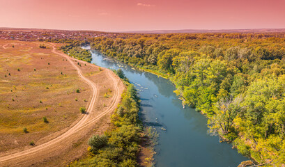 Aerial top view of a peaceful river valley among green plain. Summer scene and eco environment.