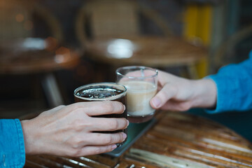 Close up of young couple hands clinking or toasting glasses of coffee talking sharing showing love and care, support, and Cheers, or business dealing, leisure time with friends idea. For Copy Space