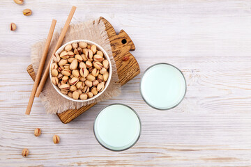 Pistachio milk in glasses and nuts in bowl. Healthy vegetarian and vegan drink, plant based milk substitute. The concept is lactose free, dairy free. Top view. 