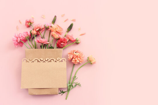 Top view image of pink flowers composition and empty note over pastel background