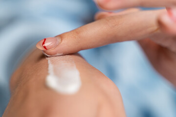 girl smears cream on her hand in blue pajamas