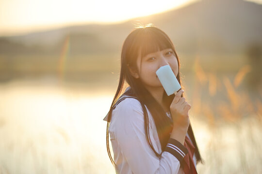 Asian High School Girls student eating ice cream in countryside with sunrise