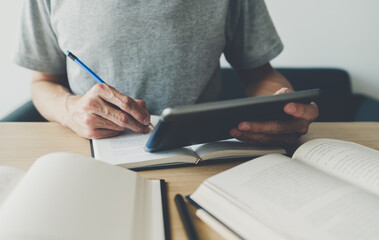 University or college student using tablet for studying, learning or reading textbook online at home. Success idea of self learning and training. Education development or knowledge improvement concept