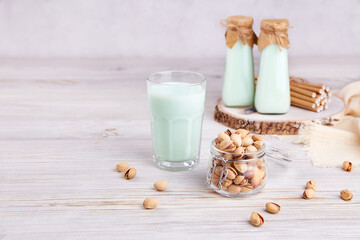 Pistachio milk in a glass and bottles, nuts in jar. Healthy vegetarian drink