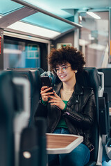 Woman tourist traveling by the train and using smartphone