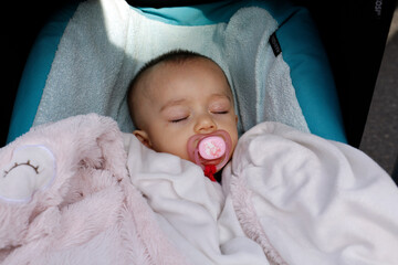 Un bébé dort avec sa molette rose
