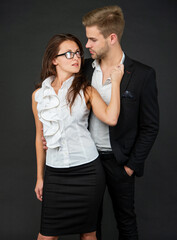 formal fashionable couple in love in business look on black background, colleague