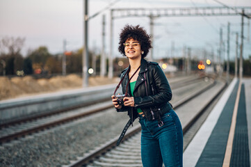 Woman waiting on a train station platform and using retro camera