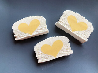 three rectangles of vanilla ice cream with yellow mango hearts on a gray background, top view, flat lay