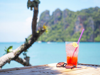 glass of cold strawberry soda juice  on bamboo table over blue sea background