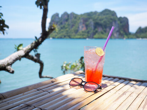 glass of cold strawberry soda juice  on bamboo table over blue sea background
