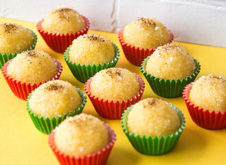 Brigadeiro de milho verde para festa junina em embalagem verde e vermelho na base amarela. Green Corn Brigadeiro for Festa Junina in green and red packaging on a yellow base.