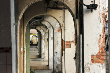 Vintage arches of a sidewalk alley lined with old shops and shrines in the world heritage site of George Town in Penang.