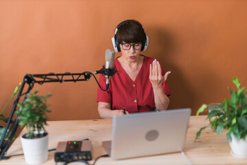 Middle-aged female radio presenter talking into the microphone and reading news - radio broadcast...