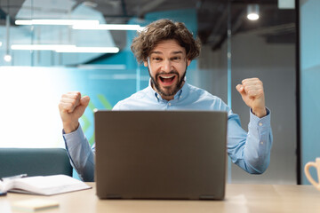 Excited businessman using pc celebrating success shaking fists screaming yes