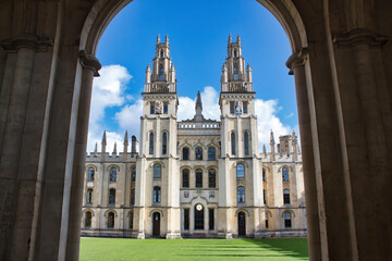 Obraz premium All Souls college, Oxford university - front view of entrance with towers and the green lawn from an archway