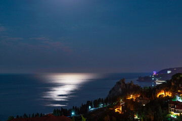 night view of seashore city with calm blue sea and shiny reflections on water. relax and vacation concept
