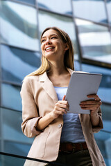 Successful businesswoman using a digital tablet while standing in front of business building.