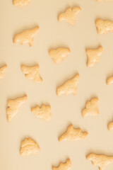 Cookies pattern in the form of dinosaurs top view on a beige background. Monochrome photo