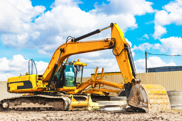Powerful excavator work on a construction site, sunny blue sky in the background. Construction equipment for earthworks.