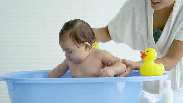 Hygienic procedures for newborn, Mother bathing her daughter in warm water, Bathing the baby in the bathroom. Newborn takes a bath in bathtub, Baby girl smile happy face while take shower